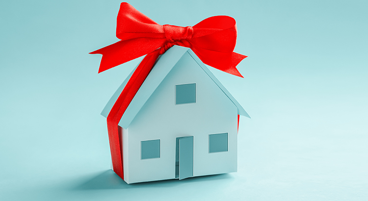 Model of a paper house tied with a gift ribbon with copy space banner