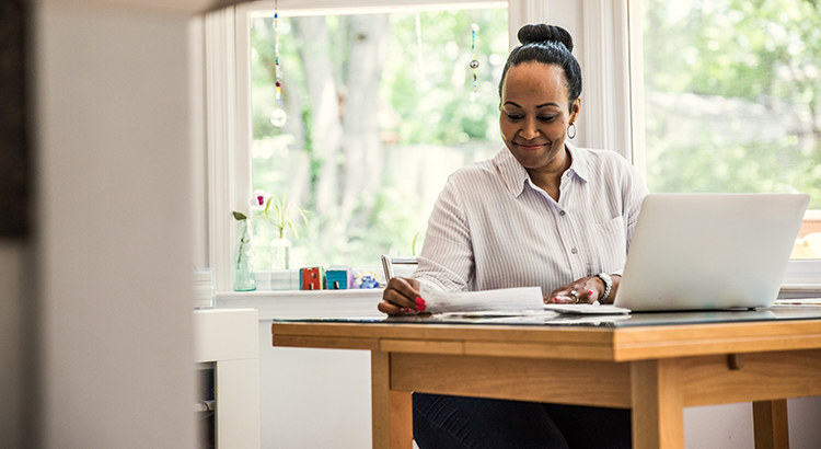 Photo of Woman working on laptop in kitchen