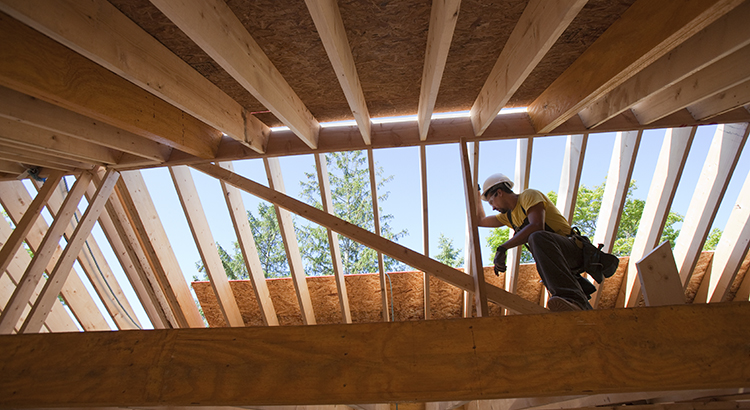 carpenter with a circular saw on rafter at a house under construction